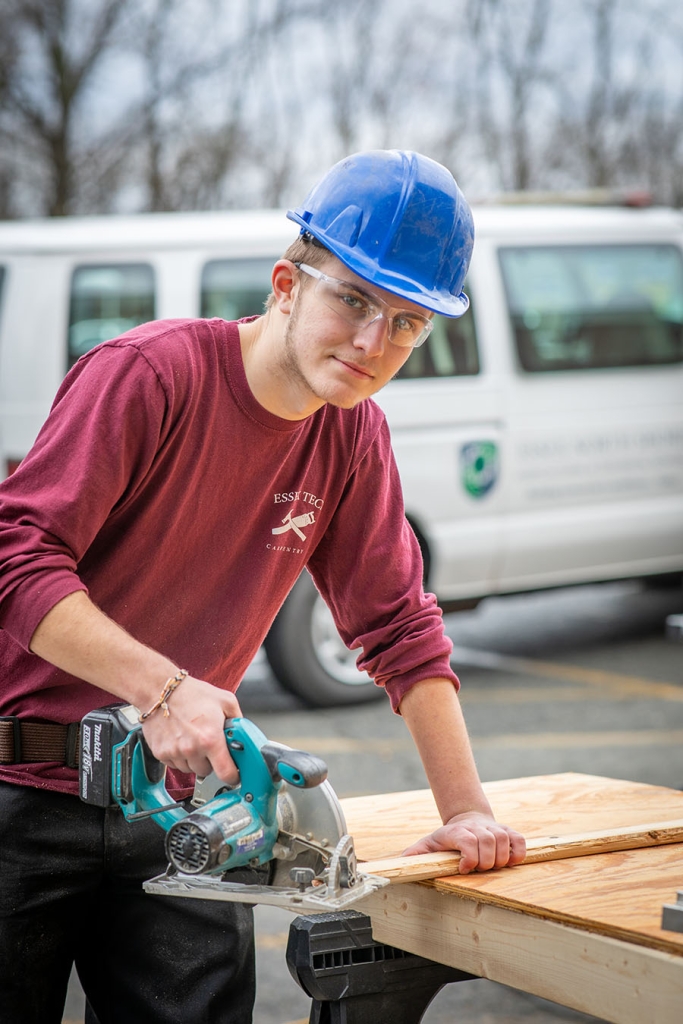 A student uses a rotary handsaw to cut wood.
