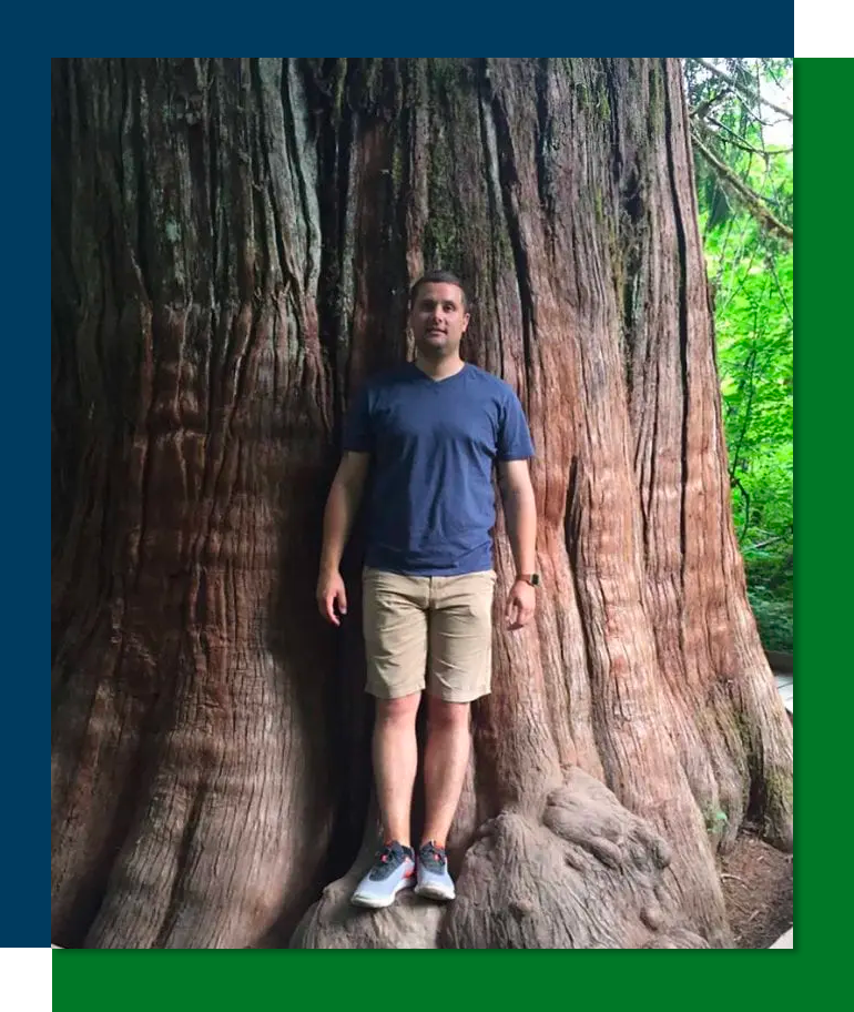 杰克梅纳德 2008 届毕业生靠在一棵非常大的树的树干上。