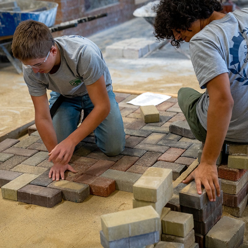 两名学生将通路砖拼在一起。
