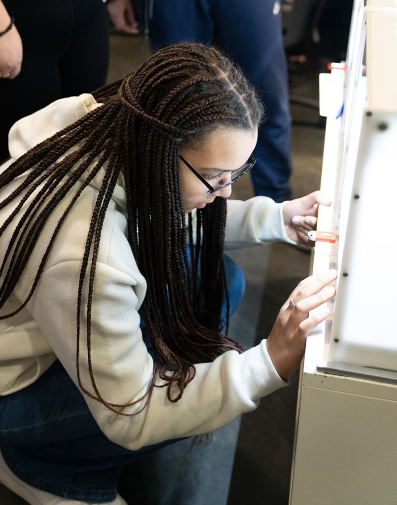Een student voert informatie in een 3D-printer in.