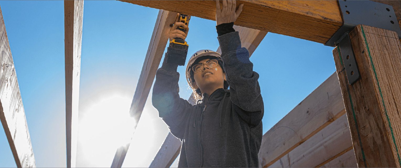 A student works on construction with the sun shining behind him.