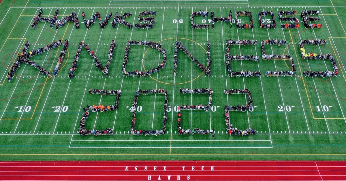 An aerial view of a football field with students spelling out Kindness Week 2022 with their bodies.
