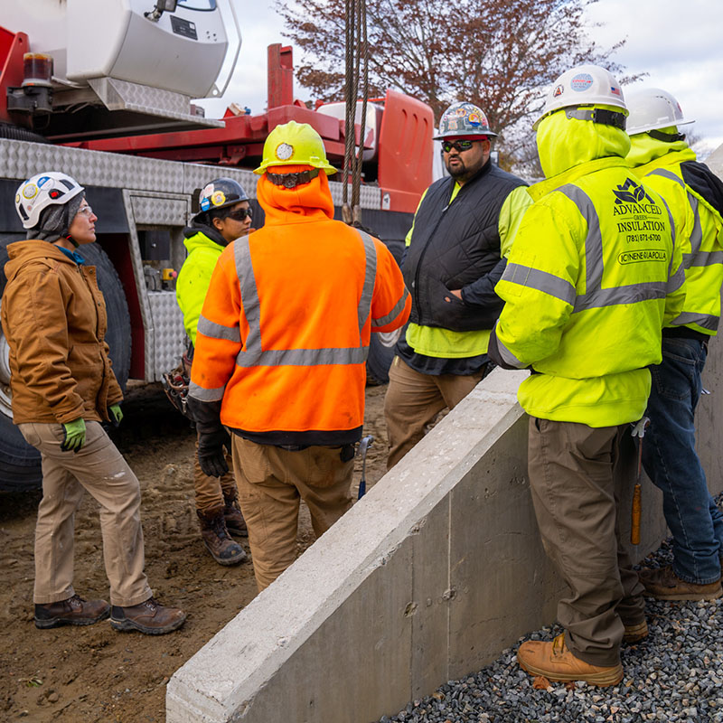 Contractor professionals from various companies stand in a group, talking.