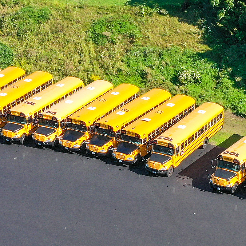 Yellow school busses parked in a lot.